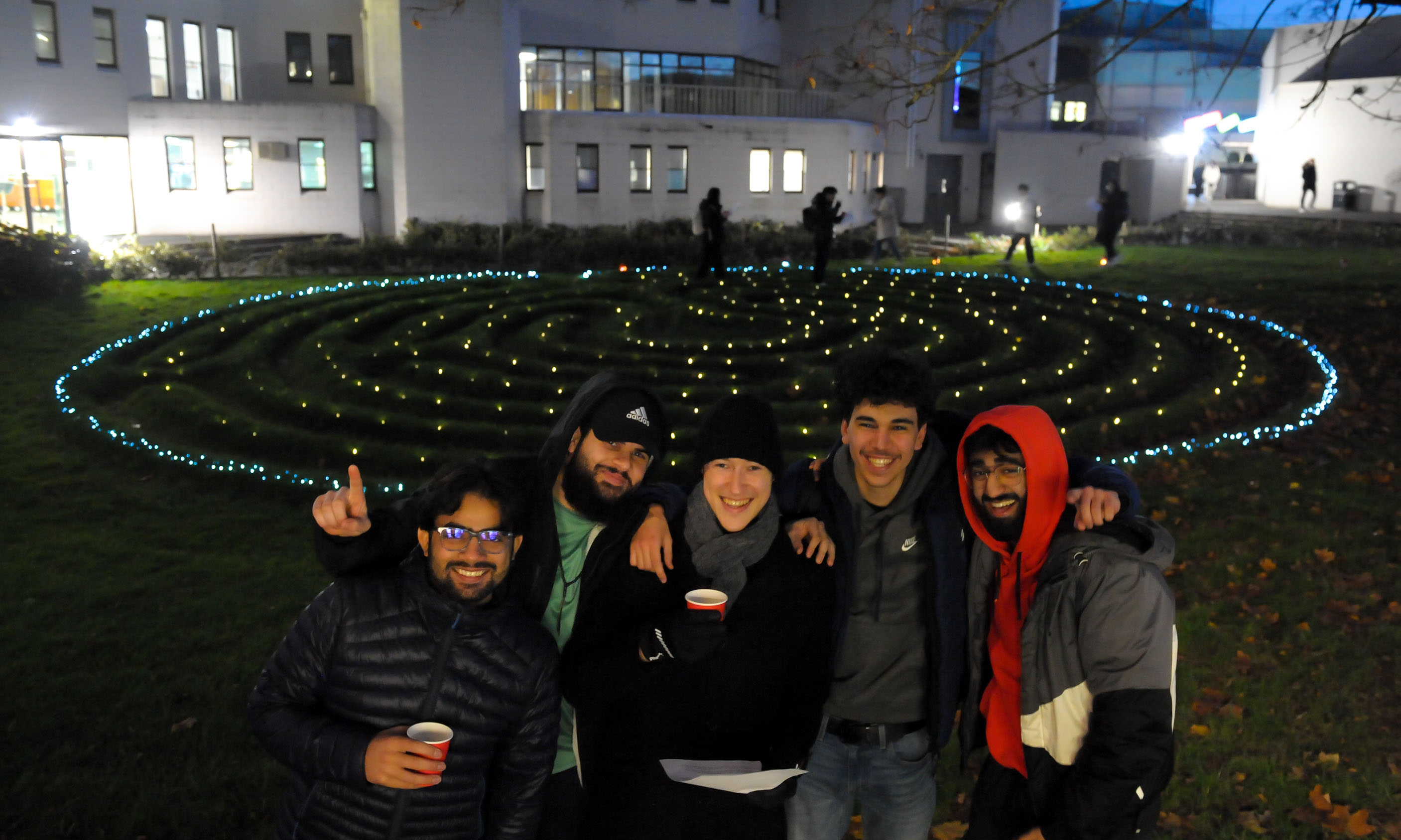 A group of students pose in front of the Christmas Light Trail