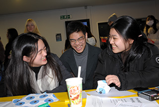 A group of students sit round a table laughing together.