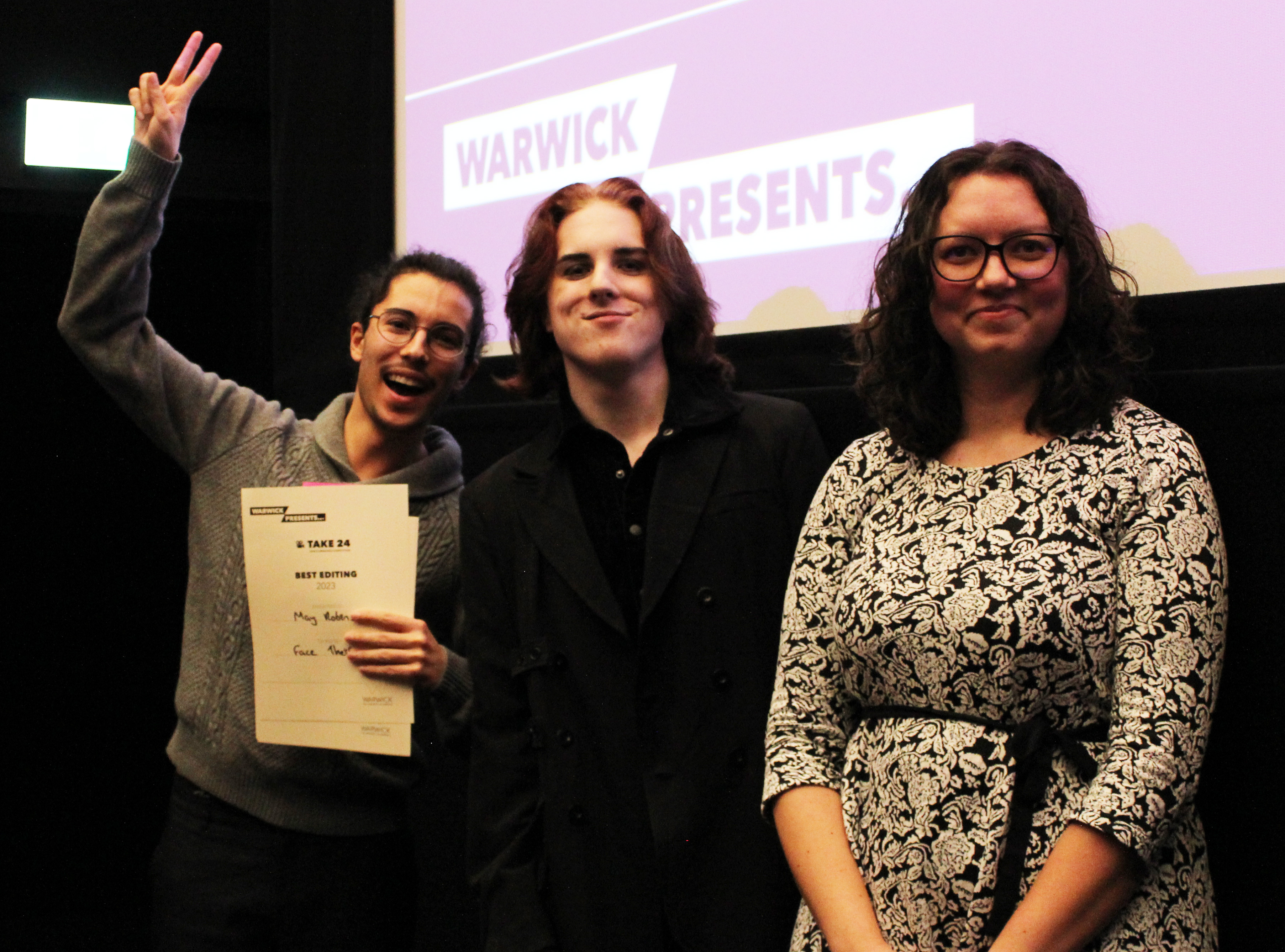 The team smile at the camera with their certificate, one holds up two fingers to mark their second award of the night.