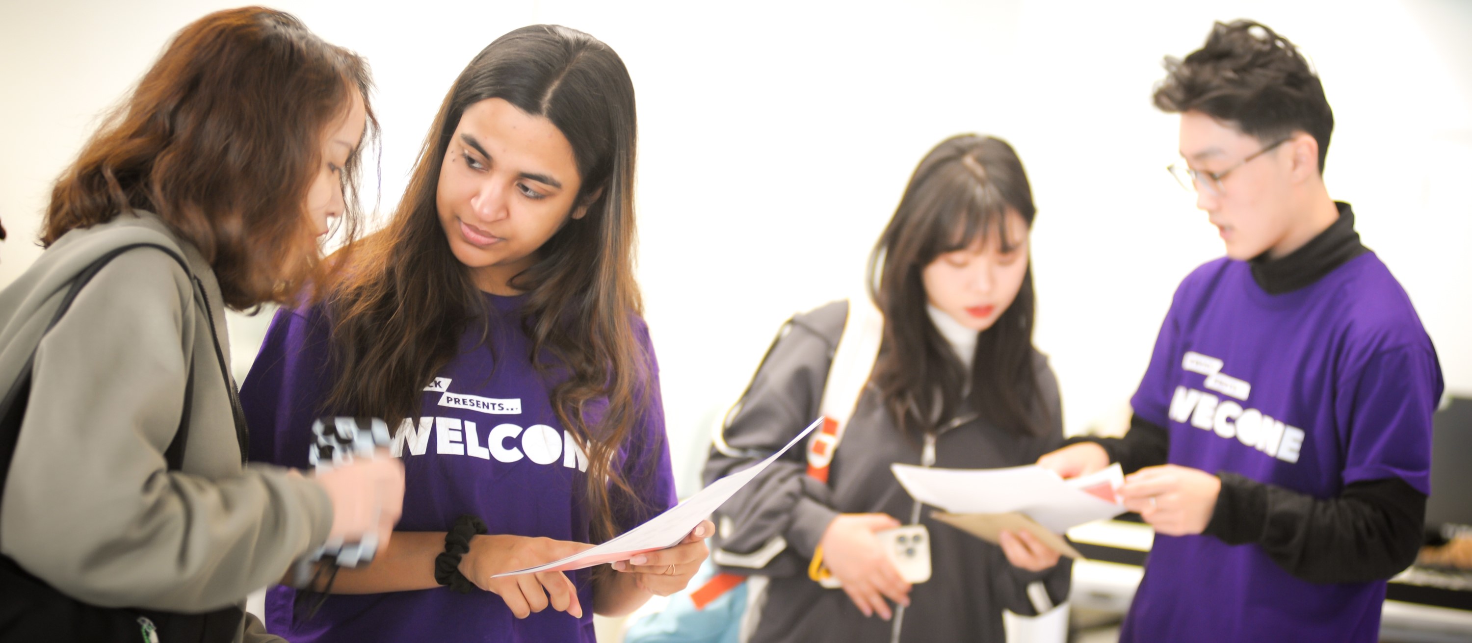 Two student Helpers support new students with information about their next steps at a Welcome Week event.