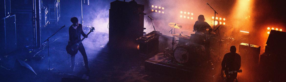 A band playing on stage, with stage lights and smoke