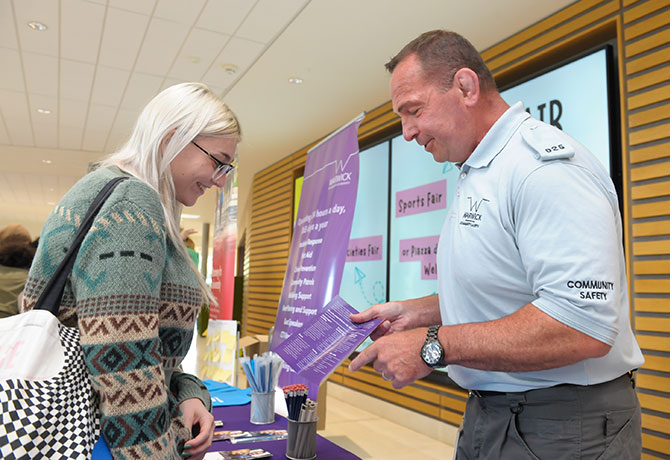 A member of the Community Safety Team shows a new student a leaflet