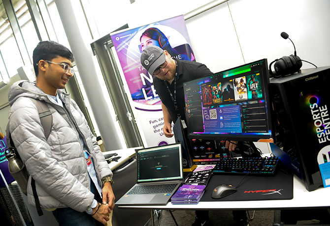 A new student admires a computer and chats to staff E-Sports