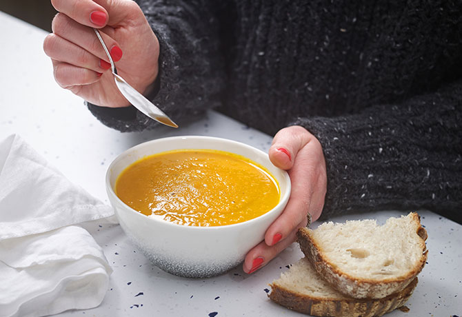 A student tucks into a warming carrot soup with slices of crusty white bread