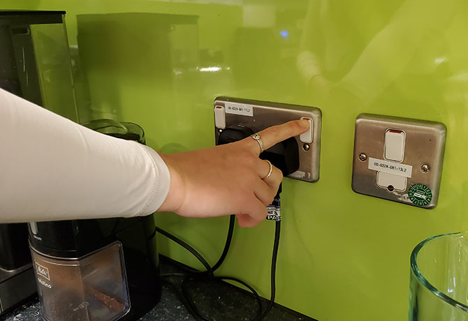 A student turns off a plug socket at the wall