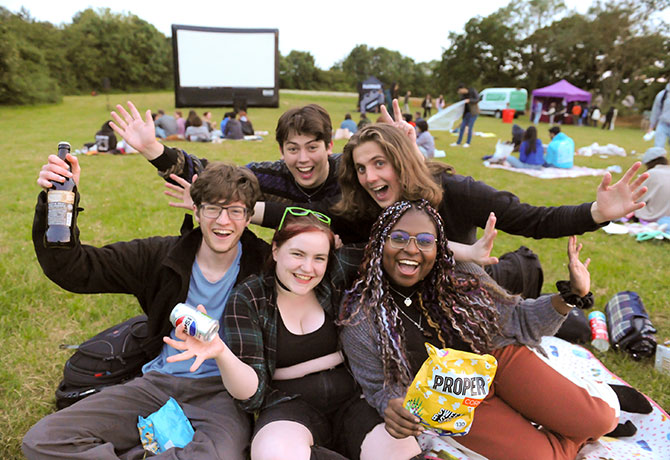 A group of students grin and pose for the camera at an outdoor film screening