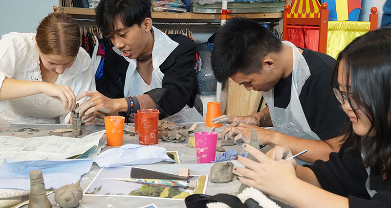 A group of students mould clay and paint with colourful pots