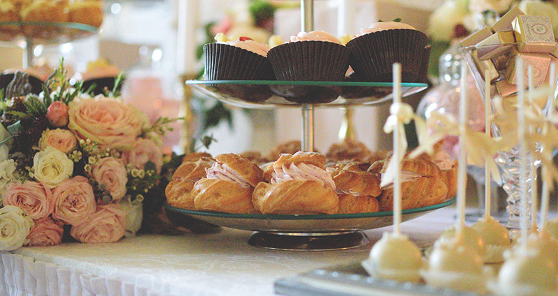 A layered tray of cupcakes and pastries, surrounded by pastel flowers