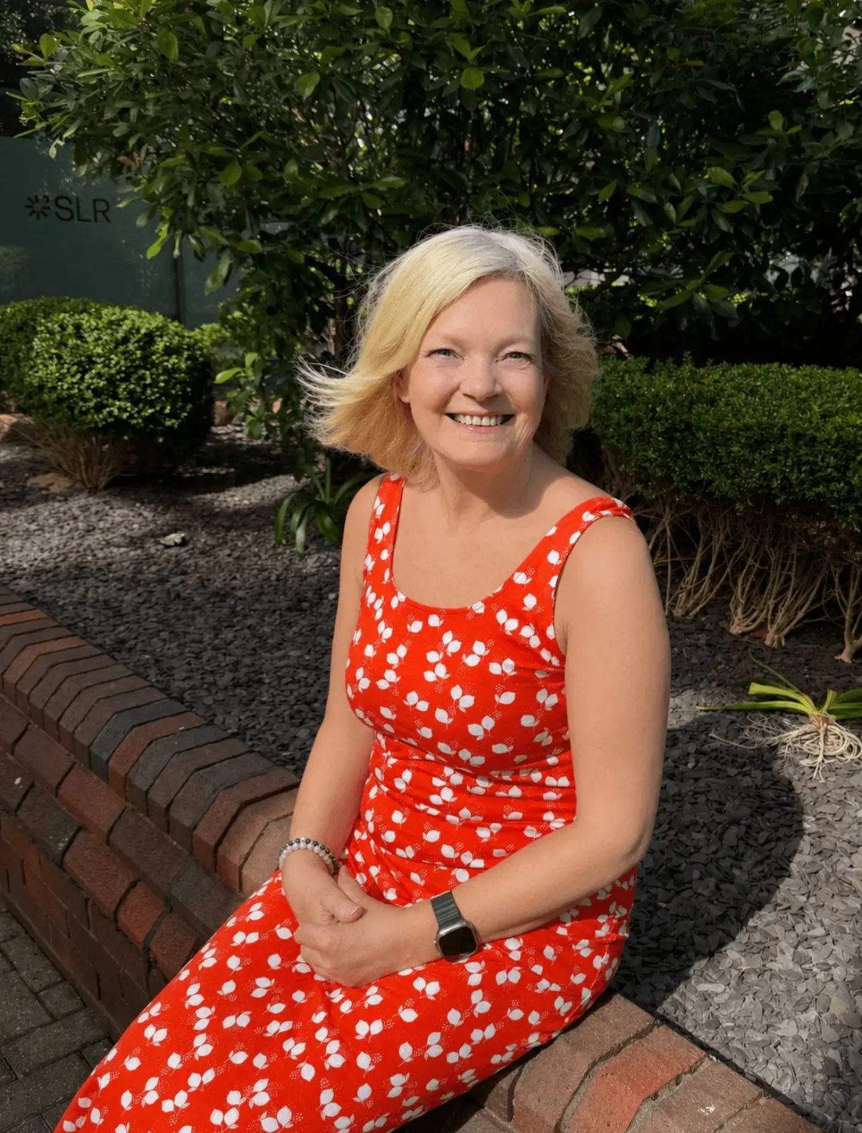 Denise sitting on a wall outdoors