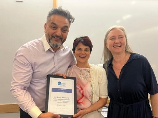 Nalita and Ruth holding an award certificate with a UALL staff member