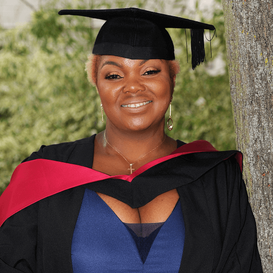 A female black student from CLL wearing her graduation gown smiling 