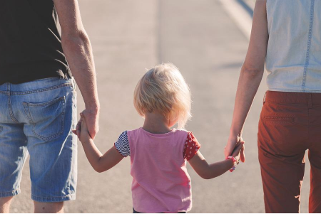a child walking among their parents holding their hands
