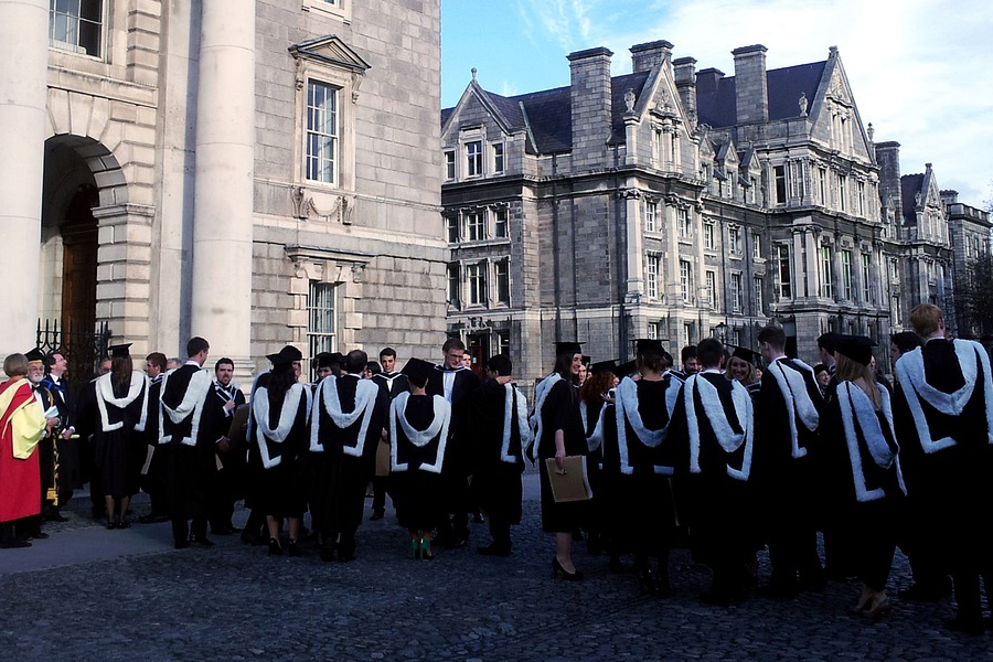 a group of students wearing graduation robe in front of some quaint buildings