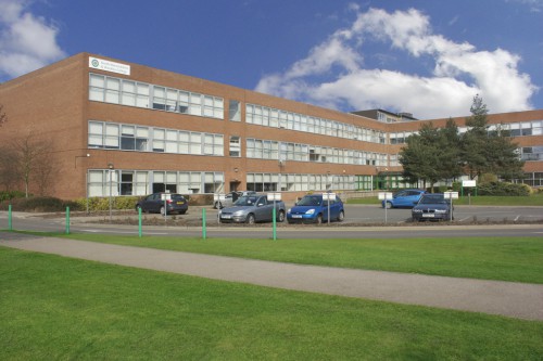 the front of a NWSLC main building showcasing the exterior, the greenery and parking 
