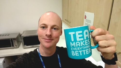 A photo of Chris Bloomer holding a mug of tea.