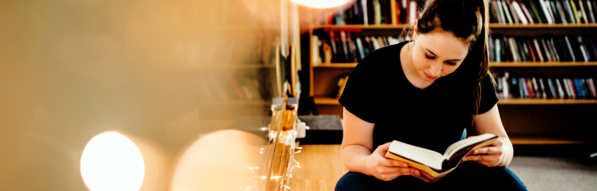 This image shows a female student in a study area reading an assigned piece of text