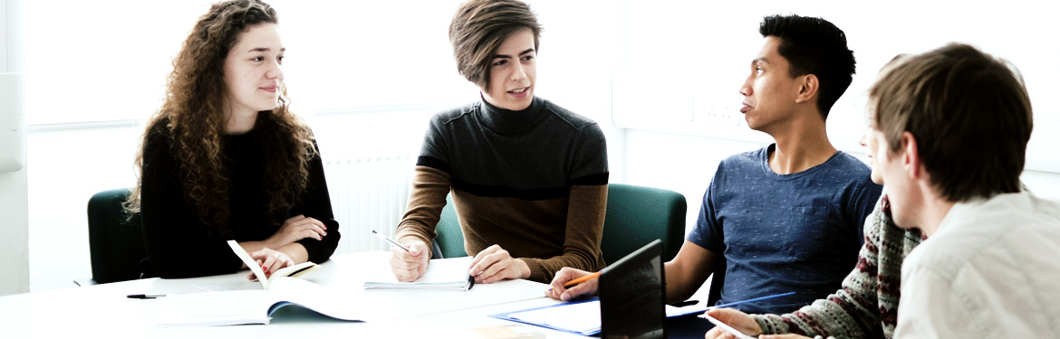 Four students sit around a table discussing postgraduate Hispanic studies/