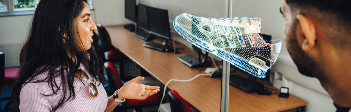 This image shows two students in a classroom exploring augmented reality technology with a holographic tennis shoe.