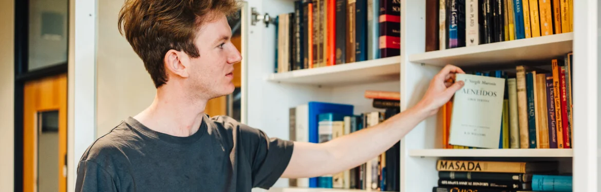 A student selecting a book from library shelves.