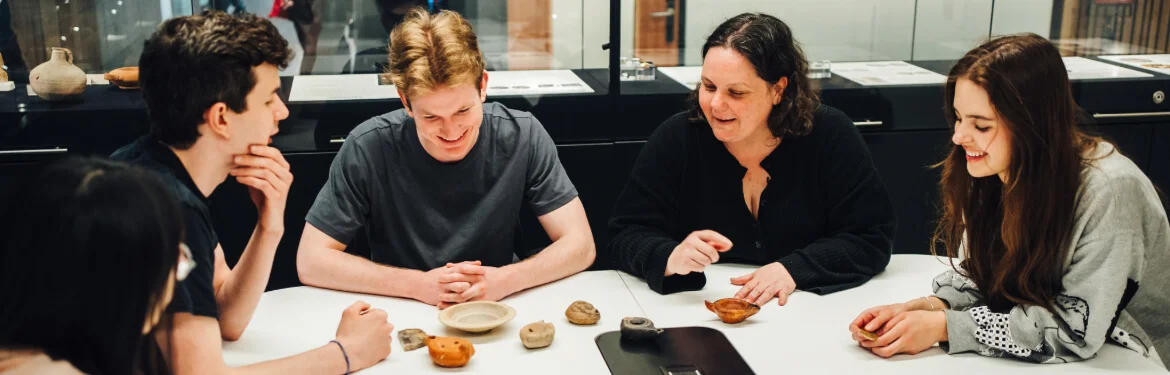 A group of students examining artefacts in a museum study space.