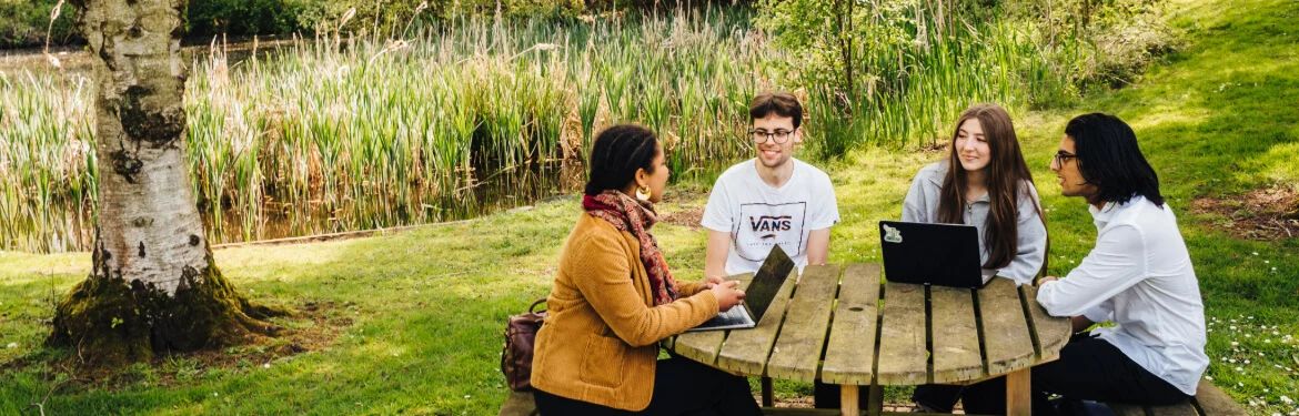 Students engaged in a study discussion at an outdoor table.