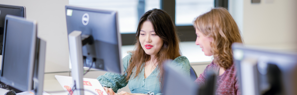 two students work together at a computer as part of their MPhil/PhD Business and Management