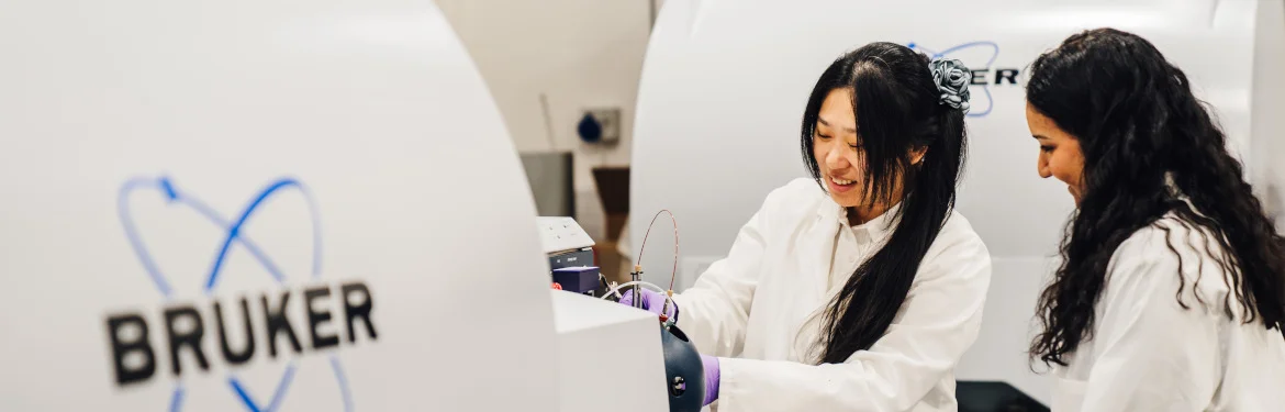 Two students operating scientific equipment in a laboratory.