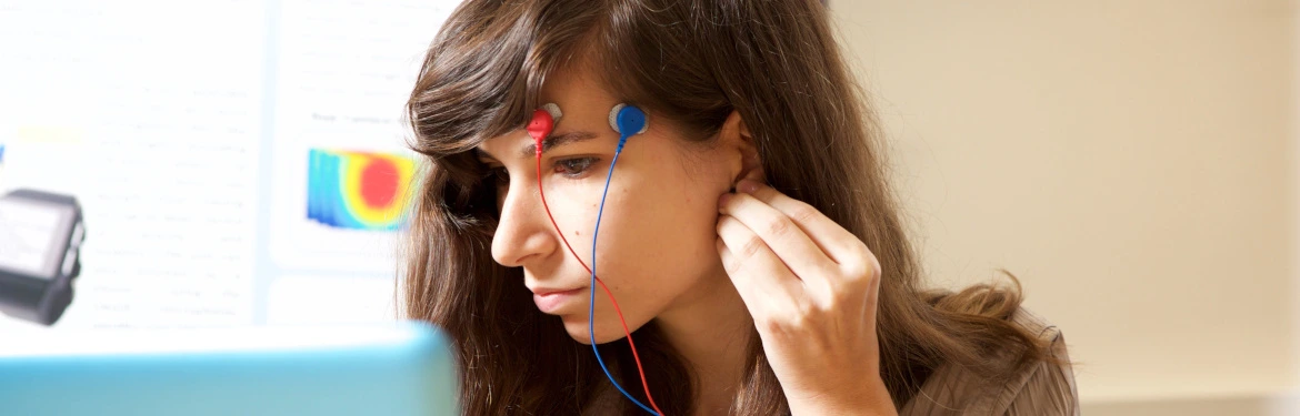 Close-up of a person with red and blue electrode sensors attached to their face,