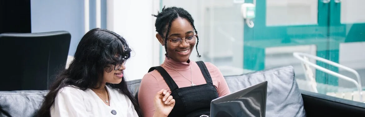 Two students working together on a laptop in a modern study space.