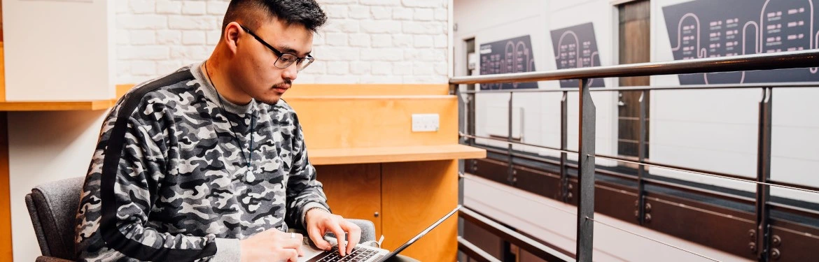 A student working on their computer in an open plan study area