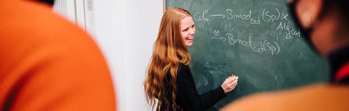A student writing on a chalk board.