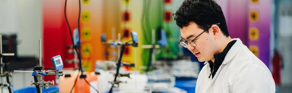 A student in a laboratory examining equipment and experiments.