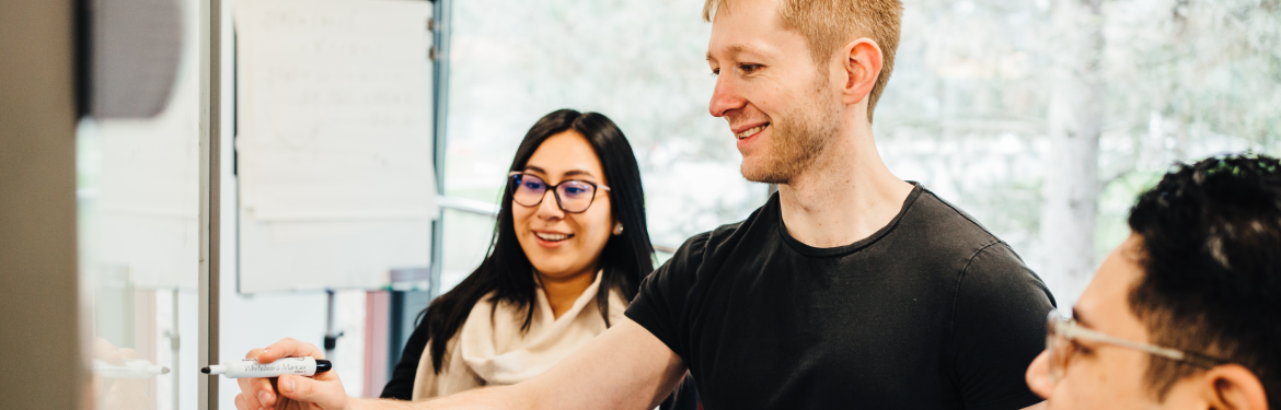 three professional looking students collaborating in front of a white board