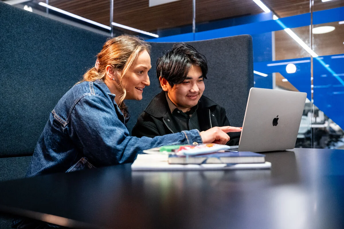 Two people working at a laptop together.