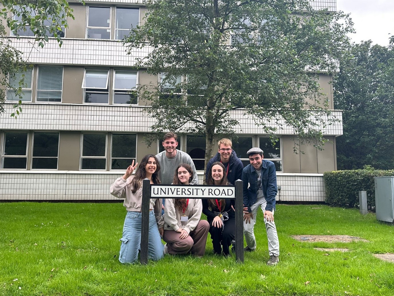 Group of students in front of a road sign that says 'University Road'