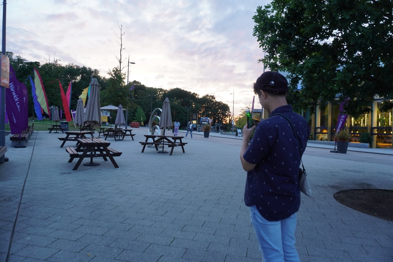 Image of student taking a photo of the Warwick piazza at sunset
