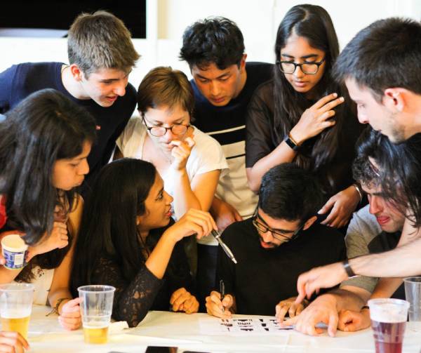 Students gathered around a table, taking part in a quiz