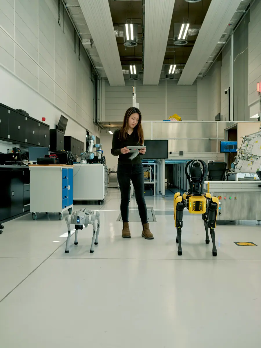Undergraduate student engaging in hands-on robotics work in a campus lab, controlling robotic devices with a tablet.