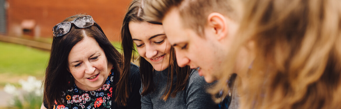 A group of students and their parents and carers looking at something.