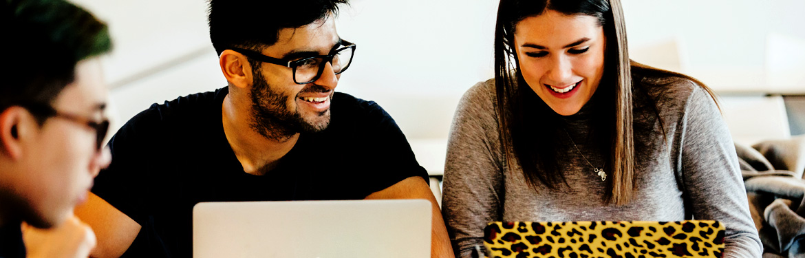 Several students laughing while working at laptops