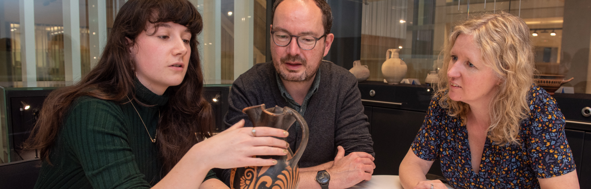 Classics students and teaching staff studying an ancient object