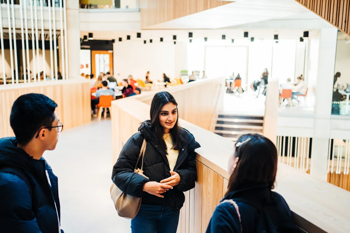 Three students having a friendly discussion in the Faculty of Arts Building on campus