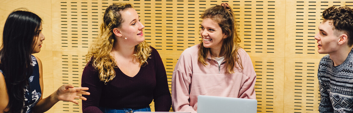 a group of students gather around a laptop to discuss Italian and classics