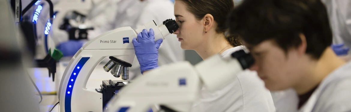 Biological sciences students looking through microscopes