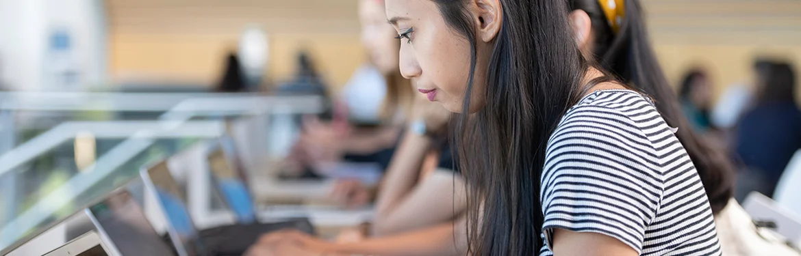 A student working on a laptop inside the Oculus building on campus