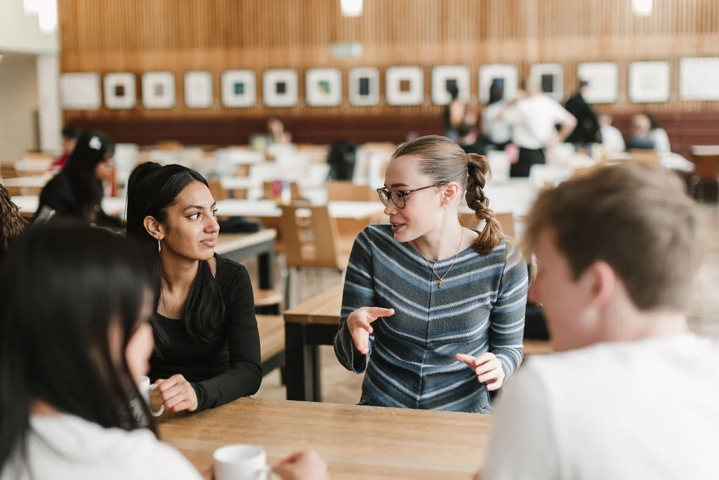 Two students having a friendly discussion in a café on campus
