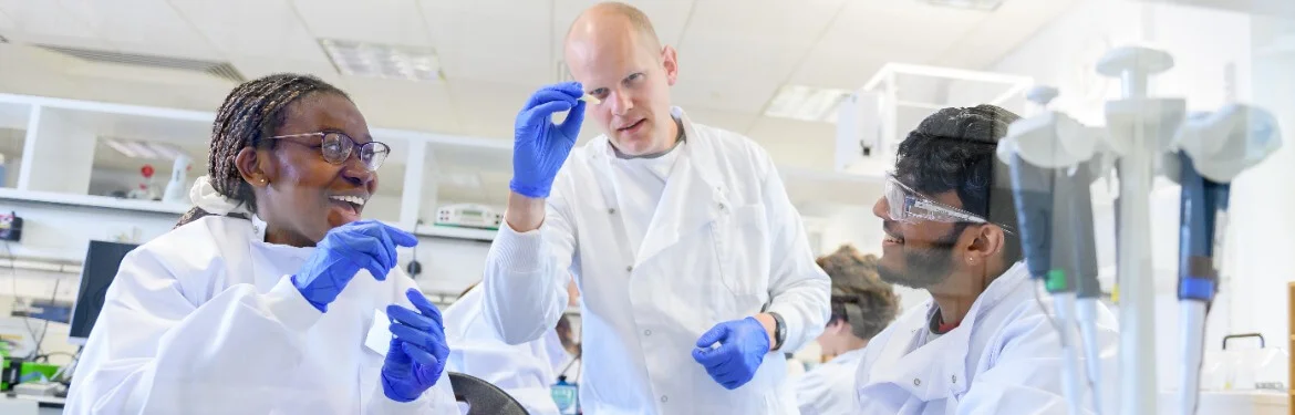 Students and an academic have a friendly discussion in a laboratory