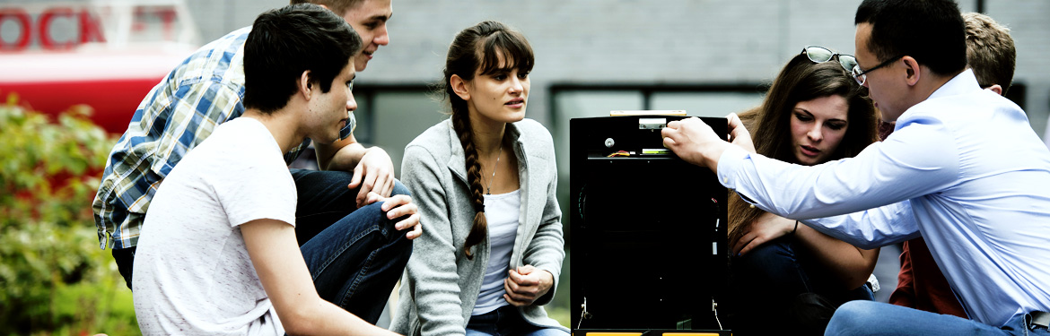 This image shows a class of students with their professor working outside on a desktop computer