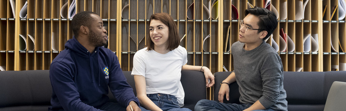 This image shows three students conversing in a common area