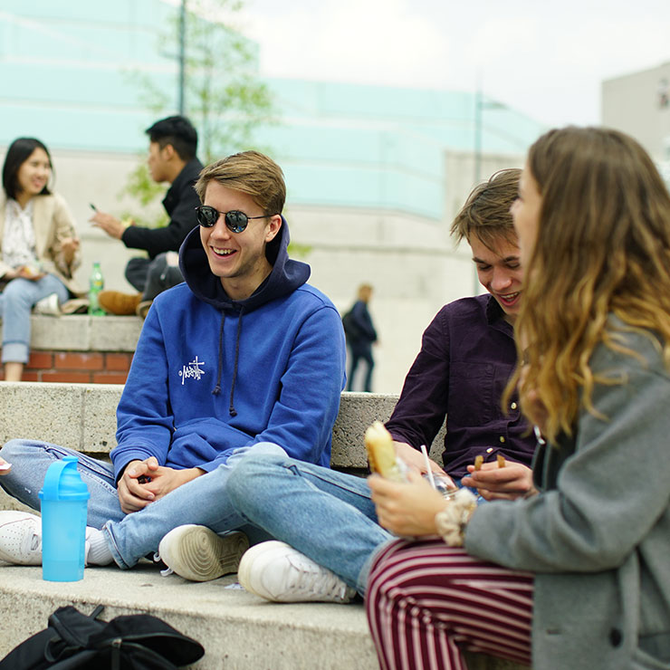 students sitting laughing on steps of piazza